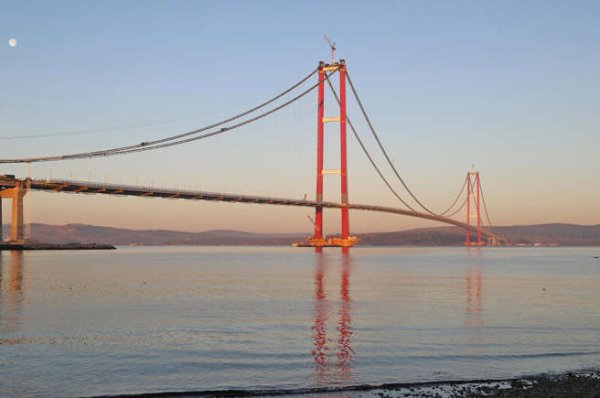 „1915“ в заглавието на моста не е препратка към това кога е построен най-дългият висящ мост в света - логично. Препратка е към годината на османската победа при Галиполи по време на Първата световна война. Въпреки че името му предизвиква смесени емоции у мнозина, мостът има ключово значение за пресичане на Дарданелите. Изграждането му отне пет години и беше завършен през 20220, така вече е най-дългият висящ в света. Изграждането му струва 2,5 милиарда евро на комшиите.
В най-високата си точка на кулите на пилоните -  мостът достига 334 метра над морското равнище, което го прави най-високият в Турция и втори мост в света. Състои се от две платна, всяка с по три ленти за движение на превозни средства плюс пешеходни пътеки от двете страни.